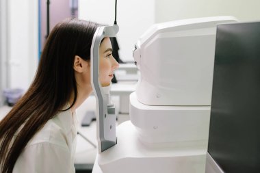 Göz arkası görüntülerini oluşturmak için optik eşkenar tomografi tomografisi. Optik tutarlılık tomografisi kullanan hastaların gözleri inceleniyor. Oftalmolog kız hastaların kornealarını tarıyor.