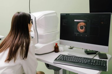 Optalmoloji kliniğinde göz taraması. Kız optik tutarlılık tomografisi kullanılarak retina muayenesinden geçiyor. Glokom, maküler dejenerasyon ve görme sorunları teşhisi için ayrıntılı göz resmi