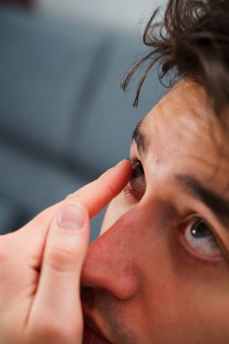 Adam miyop tedavisi için gözüne kontak lens takıyor. Optik kontakt lenslerle göz sağlığının düzeltilmesi