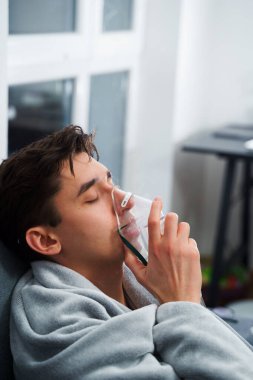 Hasta adam nebulizatörle solunum tedavisi görüyor. Evde öksürük tedavisi için nebulizör maskesiyle hava solumak