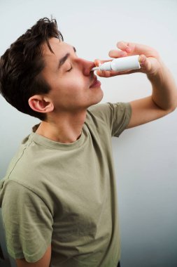 Hasta adam evde akan burundan kurtulmak için burun damlası enjekte ediyor. Adam tedavi için burun spreyi kullanıyor.