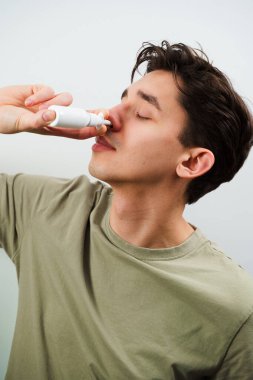 Hasta adam evde akan burundan kurtulmak için burun damlası enjekte ediyor. Adam tedavi için burun spreyi kullanıyor.