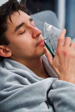 Hasta adam nebulizatörle solunum tedavisi görüyor. Evde öksürük tedavisi için nebulizör maskesiyle hava solumak
