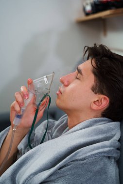 Hasta adam nebulizatörle solunum tedavisi görüyor. Evde öksürük tedavisi için nebulizör maskesiyle hava solumak