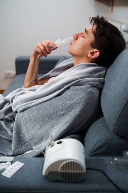 Astım krizi geçiren genç bir adam solunum cihazıyla nefes alıyor. Evde nebulizörle burun solumuş.