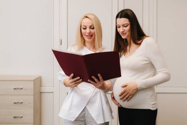 Jinekolog hamilelik kontrolü için analiz testleri gösteriyor. Jinekolog, tıbbi sonuçları hamile hastaya bildirdi.