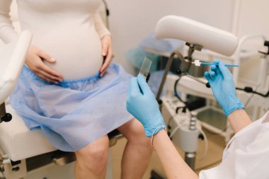 Jinekoloji konsültasyonu. Jinekolog, hamilelik merkezindeki PAP için konsolosluk yapar ve karalama analizi yapar.