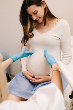 Rahmin elle muayene edilmesi, jinekoloji kliniğinde bebek fetüs embriyosu çıkıntıları. Jinekolog klinikte kontrol sırasında hamile kadının karnını muayene ediyor.