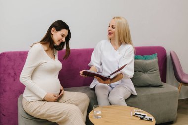 Jinekolog, hamile bir kadının kan testinin sonuçlarını tartışıyor. Jinekolog randevusu sırasında hastaya yüksek hemoglobin ve kan basıncı hakkında danışmanlık yapmak.