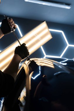 PDR için parlak bir arabanın çatısında çekme aleti kullanmak, basıncı tam olarak ayarlamak. Uzman, metali yeniden boyanmadan eski haline getirmek için ileri çekiş aracı kullanıyor