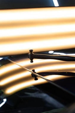 PDR teknisyeni, kaputtaki çukur düzeltmesini kontrol etmek için yansıma lambasına özel bir çekiç tutuyor. Acısız bir araba göçüğü.