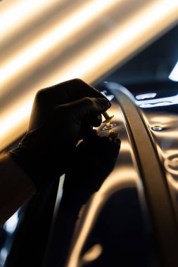 Hassas ve acısız bir tamir seansı sırasında araba yüzeyine yapıştırıcı sürmüş. Yüksek yansıma aydınlatması kusursuz araba göçüğü temizleme için görünürlüğü artırır