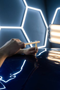 PDR gelişmiş tekniği acısız çukur temizleme onarımı tamamlanır. Kesinlik tıkırdatma aracı parlak altıgen LED ışıklar altında ağrısız çukur onarım sırasında araba yüzeyini rafine eder