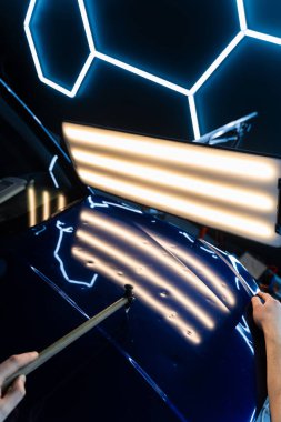 PDR teknisyeni, çarpma aletini ve çekiç kombinasyonunu dolu izlerini düzeltmek için kullanır. Odaklanmış vuruşlar boyaya zarar vermeden metali yeniden hizaladı. Devrilmiş bir aletle kontrol edilen musluklar dolu ile bükülmüş metali yeniden şekillendirir