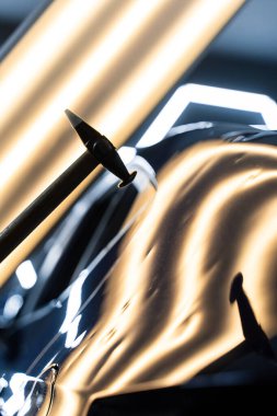 Ağrısız çukur onarma PDR hassasiyet için ışık yansıması altında ezilmeyi içerir. Teknisyen, acısız çukur onarımı sırasında arabanın kaputundaki göçükleri çıkarmak için PDR araçları kullanıyor.