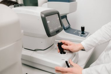 Otomatik fraktör görme düzeltmesi ve göz sağlığı değerlendirmesi için kesin ölçümler sağlar. Göz muayenesi sırasında otomatik fraktörü ayarlayan bir optometristin yakın çekimi.