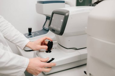 Otomatik fraktör görme düzeltmesi ve göz sağlığı değerlendirmesi için kesin ölçümler sağlar. Göz muayenesi sırasında otomatik fraktörü ayarlayan bir optometristin yakın çekimi.