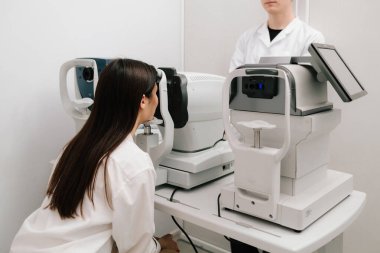 Modern otorefraktör ve OKT makineleriyle göz muayenesi. Otomatik fraktör kırılma hatalarını ölçer, gözlük veya lens reçetelerinin yüksek doğruluk ve verimlilikle belirlenmesine yardımcı olur.