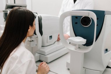 Modern otorefraktör ve OKT makineleriyle göz muayenesi. Otomatik fraktör kırılma hatalarını ölçer, gözlük veya lens reçetelerinin yüksek doğruluk ve verimlilikle belirlenmesine yardımcı olur