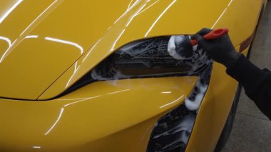 4K video servisinde spor araba farlarını sabun köpüğü ve fırçayla temizleme işlemi yapılıyor. Araba farları köpük ve yumuşak fırçayla temizleniyor
