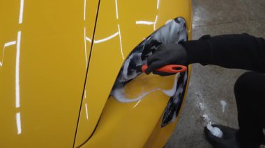 Araba farları köpük ve yumuşak fırça ile temizleniyor. 4K video. Spor araba farlarını temizleme işlemi. Sabun köpüğü ve fırçayla yıkayın.