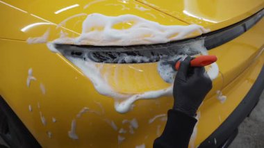 Farları köpüklü ve fırçalı 4K video ile yıkama prosedürü. Araba yıkamada temizlik fırça ve köpükle yapılır.