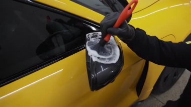 4K videosundaki araba temizliği titiz yapılmış. Sabunlu çözeltiyi arabaların aynasına sürmenin detaylı prosedürü bir fırça kullanarak.