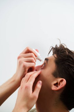 Adamın gözü tahriş sorunu yüzünden damlıyor. Evde göz damlası ile göz tedavisi uygulanıyor. Adam alerji tedavisi için göz damlası kullanıyor.