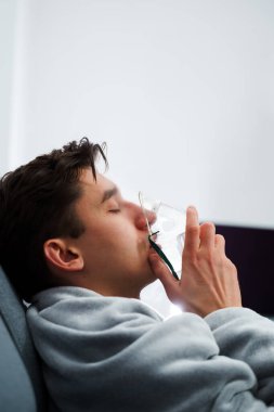 Hasta adam nebulizatörle solunum tedavisi görüyor. Evde öksürük tedavisi için nebulizör maskesiyle hava solumak