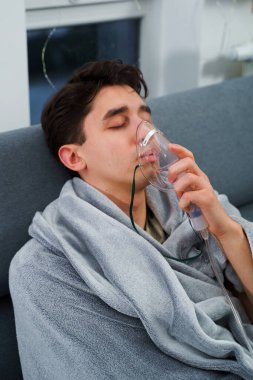 Hasta adam nebulizatörle solunum tedavisi görüyor. Evde öksürük tedavisi için nebulizör maskesiyle hava solumak