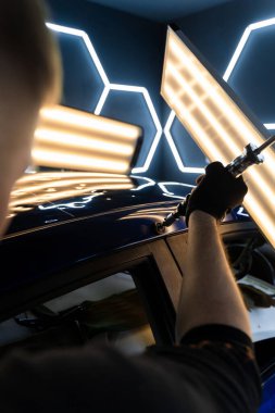 Uzman, metali yeniden boyanmadan eski haline getirmek için ileri çekiş aracı kullanıyor. PDR için parlak bir arabanın çatısında çekme aracı kullanmak, basıncı tam olarak ayarlamak