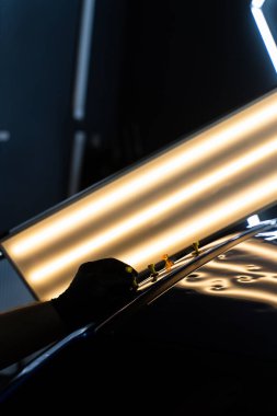 Ağrısız çukur onarma işlemi sırasında LED ışıklarının altındaki çökmüş bir arabanın çatısına birden fazla yapıştırıcı şeridi takılmış. Yapıştırıcı sekmeleri yüzeyi hatasız bir bitiş için hizalamaya ve onarmaya yardımcı olur