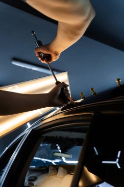 PDR araba göçüğü temizleme, yapıştırıcı çekici ve yansıtma tahtası kullanarak. Araç gövdesindeki yüzeysel kusurları gidermek için özel aletler. Arabanın çatısında çekiçle acısız bir çukur açılır.