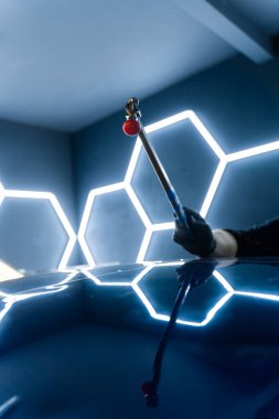 Araba panelinin içinden acısız tamir aletleri çalışıyor. Teknisyen çeliği tamir etmek için koz çubuğu kullanıyor. Göçük arkasından kullanılan PDR çubuk aracı klasik tamir tekniğini gösterir