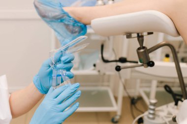 Jinekolog klinikte bakteri muayenesi için vajinadan örnek alıyor. Jinekolog muayene koltuğunda hamile kadını muayene ediyor.