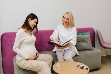 Jinekolog, hamile bir kadının kan testinin sonuçlarını tartışıyor. Jinekolog randevusu sırasında hastaya yüksek hemoglobin ve kan basıncı hakkında danışmanlık yapmak.