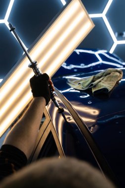 Uzman, metali yeniden boyanmadan eski haline getirmek için ileri çekiş aracı kullanıyor. PDR için parlak bir arabanın çatısında çekme aracı kullanmak, basıncı tam olarak ayarlamak