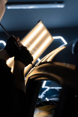 Uzman, metali yeniden boyanmadan eski haline getirmek için ileri çekiş aracı kullanıyor. PDR için parlak bir arabanın çatısında çekme aracı kullanmak, basıncı tam olarak ayarlamak