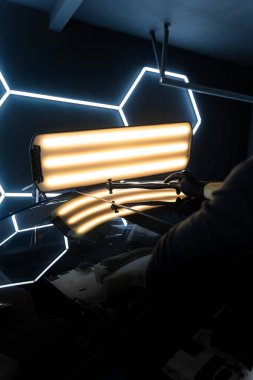 PDR Acısız araba göçüğü temizleme. PDR teknisyeni, kaputtaki çukur düzeltmesini kontrol etmek için yansıma lambasına özel bir çekiç tutuyor.