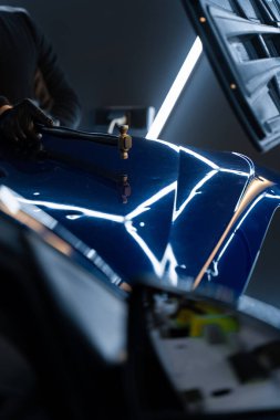 PDR teknisyeni, çarpma aletini ve çekiç kombinasyonunu dolu izlerini düzeltmek için kullanır. Odaklanmış vuruşlar boyaya zarar vermeden metali yeniden hizaladı. Devrilmiş bir aletle kontrol edilen musluklar dolu ile bükülmüş metali yeniden şekillendirir