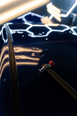 PDR teknisyeni, çarpma aletini ve çekiç kombinasyonunu dolu izlerini düzeltmek için kullanır. Odaklanmış vuruşlar boyaya zarar vermeden metali yeniden hizaladı. Devrilmiş bir aletle kontrol edilen musluklar dolu ile bükülmüş metali yeniden şekillendirir