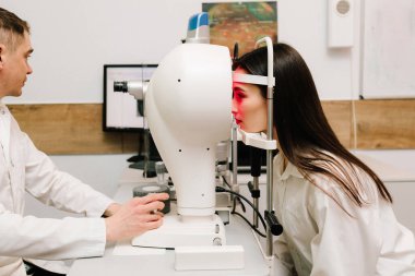 Korneanın şekli ve gücünün görsel tanımı için kornea topografisi göz görme testi. Kornea topografının kırmızı ışığı topoğrafya sınavında kadının üzerine parlıyor