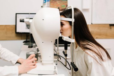 Korneanın şekli ve gücünün görsel tanımı için kornea topografisi göz görme testi. Kornea topografının kırmızı ışığı topoğrafya sınavında kadının üzerine parlıyor