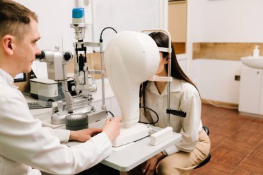 Korneanın şekli ve gücünün görsel tanımı için kornea topografisi göz görme testi. Kornea topografının kırmızı ışığı topoğrafya sınavında kadının üzerine parlıyor