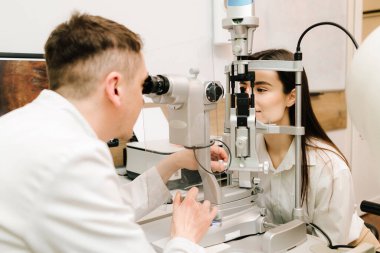 Göz farı ve kornea teşhisi, göz hekimliği kliniğinde. Kesik lambanın gözündeki ışık incelenmek için gözleri ve kızın korneası için.