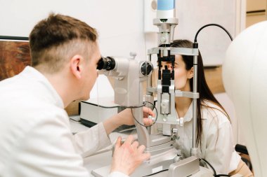 Göz farı ve kornea teşhisi, göz hekimliği kliniğinde. Kesik lambanın gözündeki ışık incelenmek için gözleri ve kızın korneası için.