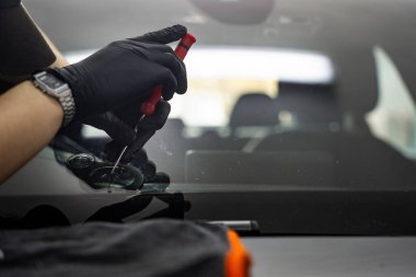 Teknisyen cam çipine kontrollü basınç uygulamak için metal bir alet kullanıyor. Awl, ön cam çatlağının kenarına yerleştirilir. Teftiş ya da çip hazırlığı için.