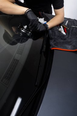 Profesyonel bir köprü aracı ve reçine ile ön cam çatlağı tamiri başladı. Teknisyen, arabanın ön camını yüksek basınçlı reçine enjeksiyonuyla onarmak için köprü aracı kullanıyor.