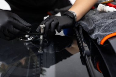 Profesyonel bir köprü aracı ve reçine ile ön cam çatlağı tamiri başladı. Teknisyen, arabanın ön camını yüksek basınçlı reçine enjeksiyonuyla onarmak için köprü aracı kullanıyor.