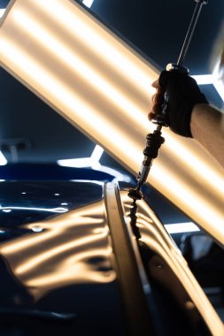 PDR için parlak bir arabanın çatısında çekme aleti kullanmak, basıncı tam olarak ayarlamak. Uzman, metali yeniden boyanmadan eski haline getirmek için ileri çekiş aracı kullanıyor